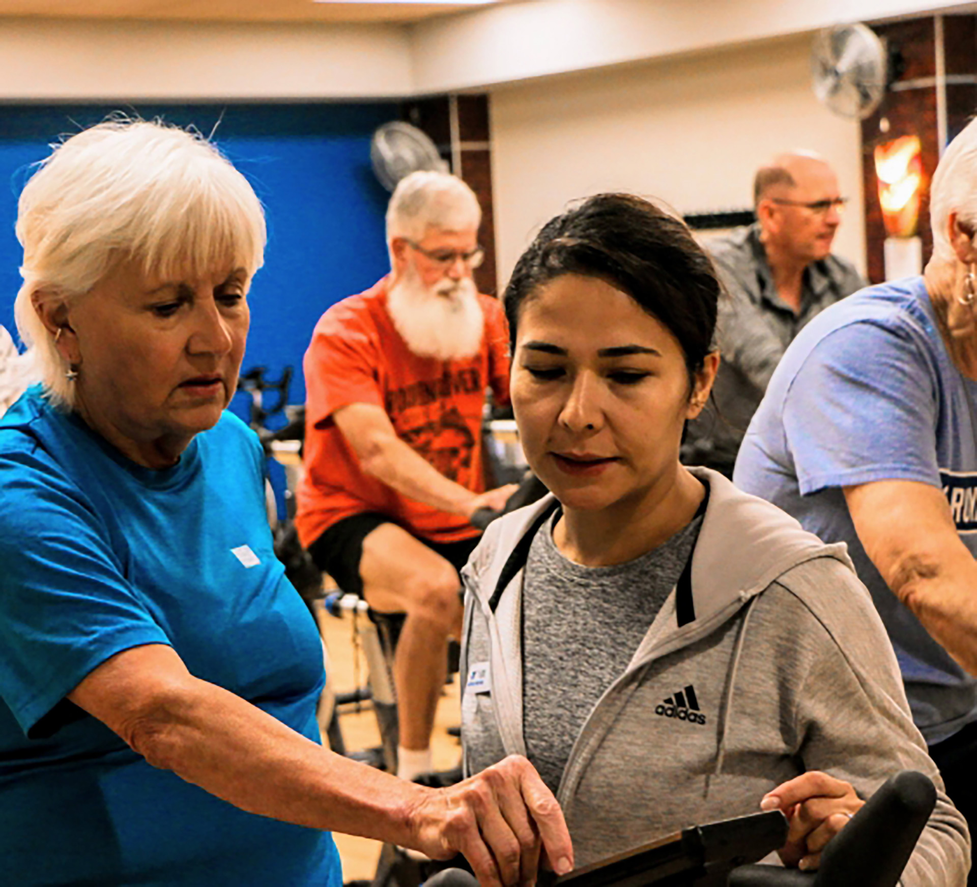 YMCA instructor assisting a participant on cardio equipment in a group class