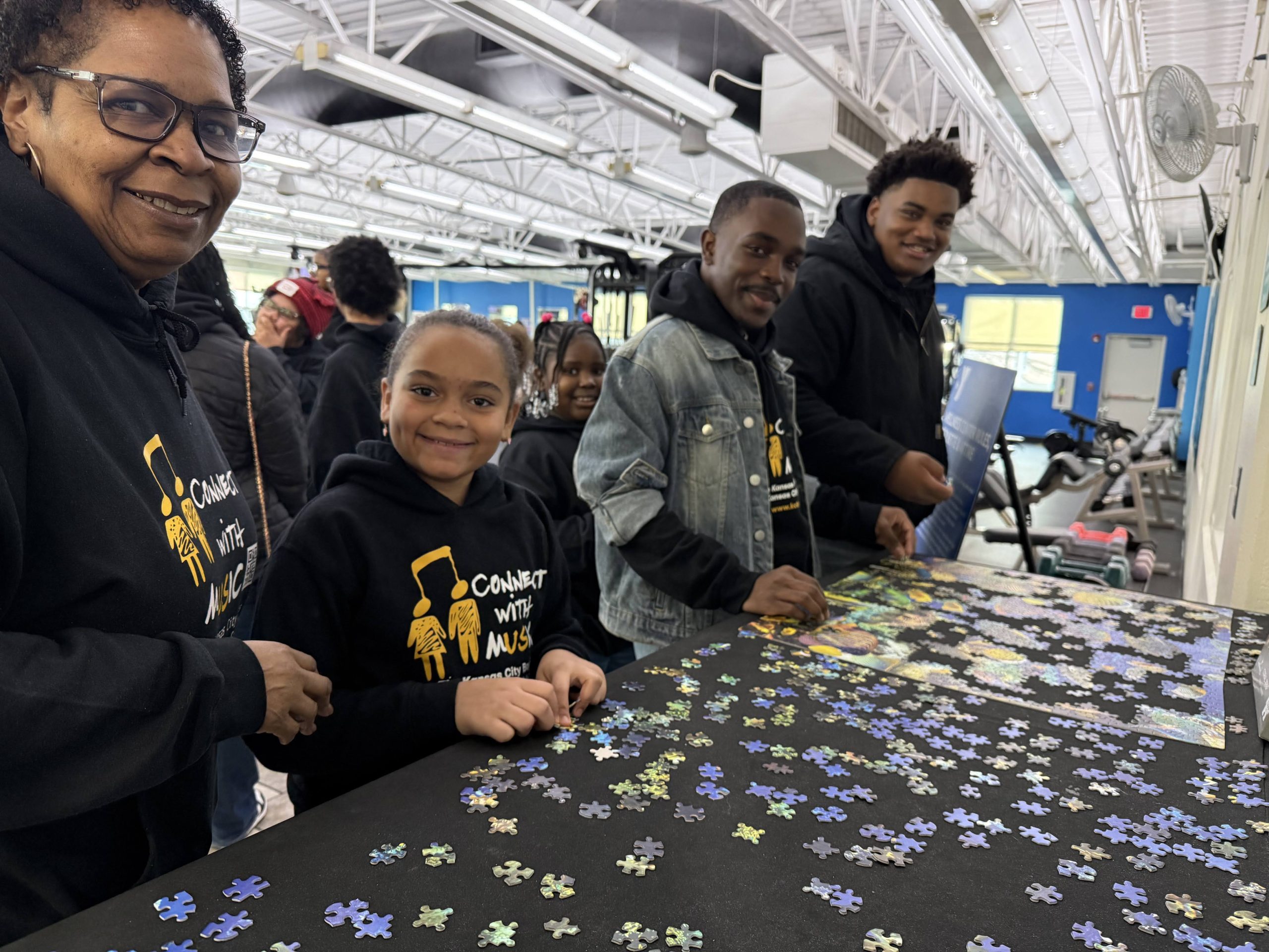 Family and youth smiling around a jigsaw puzzle at a YMCA community table