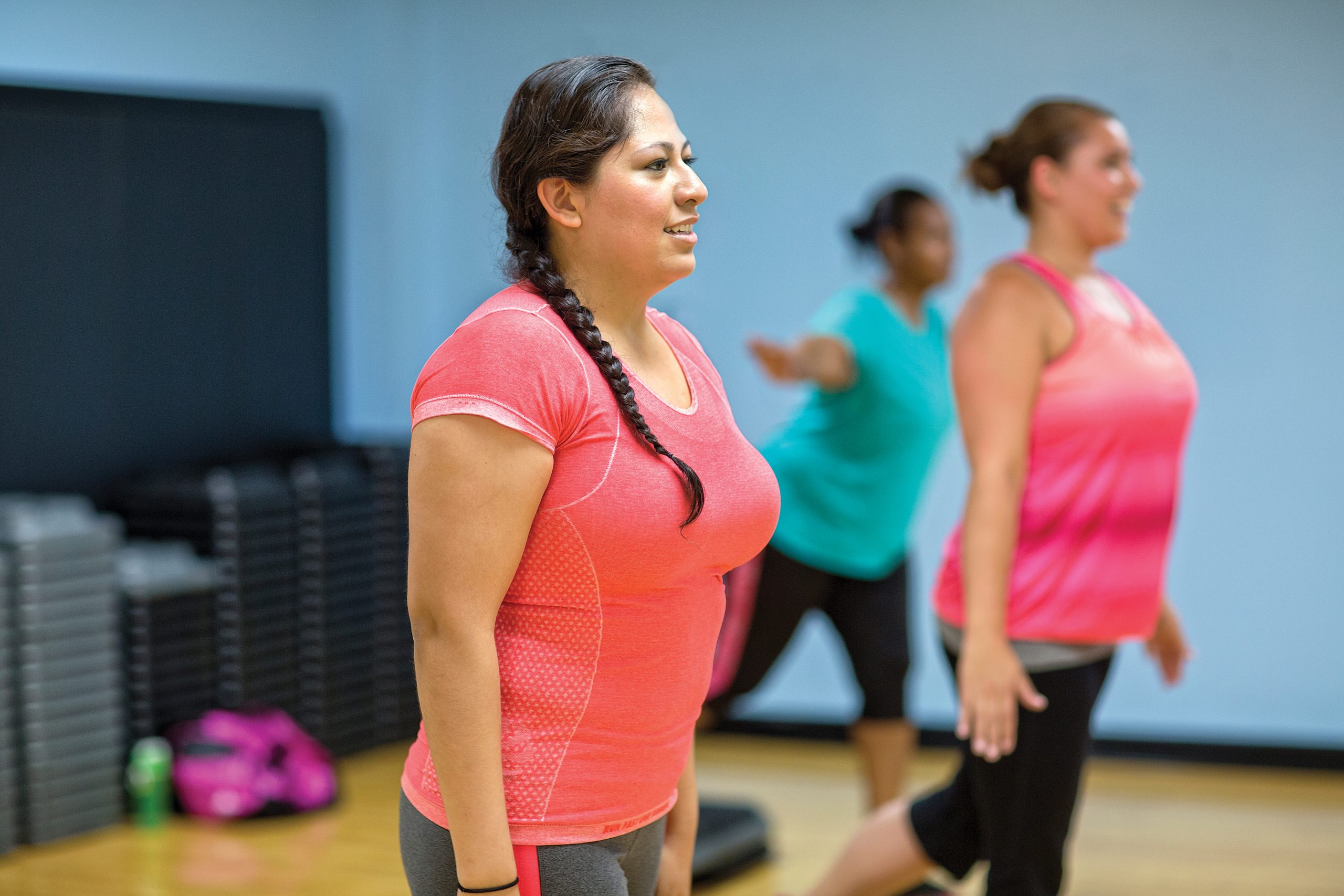 Women in bright activewear standing in a group fitness studio class