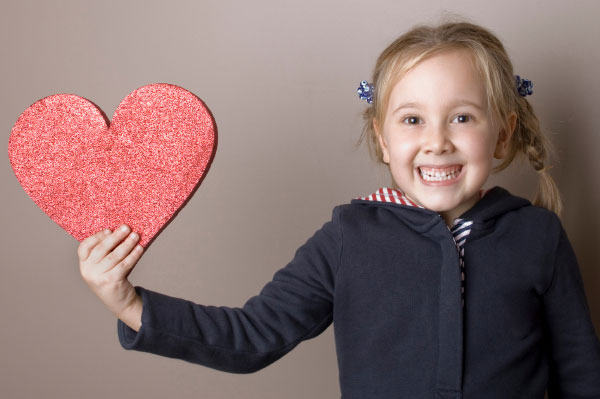 Young girl hold a glittery heart cut out in support of heart health for the Kansas City YMCA