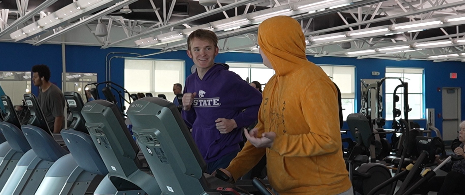 An adult mentor and youth match with Big Brothers Big Sisters enjoy time together exercising on treadmills at a greater Kansas City location as part of the Y's partnership