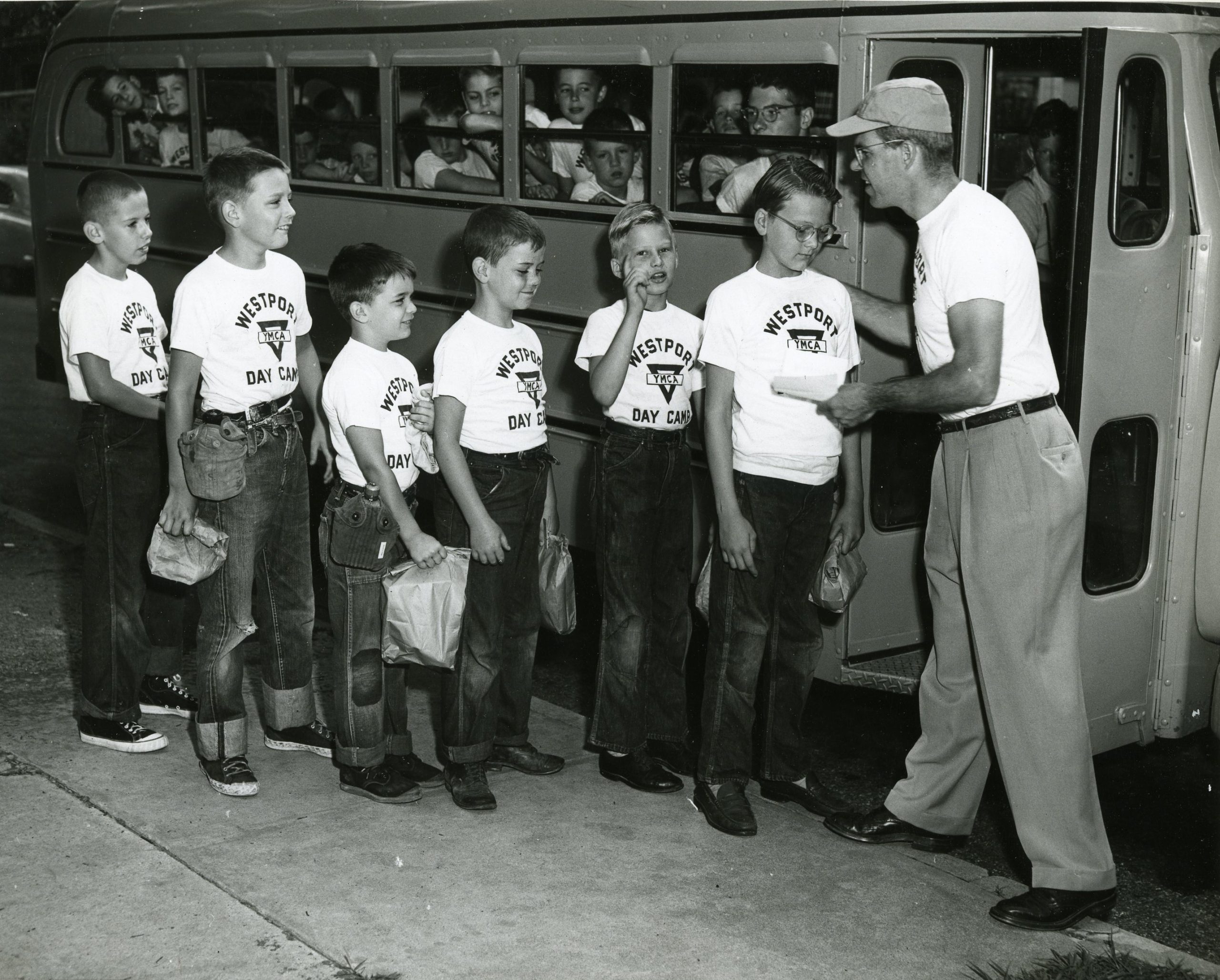 Historic photo of boys lined up to get on bus for summer day camp.