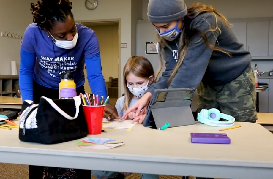2 YMCA team members instructing a student on homework at a desk.