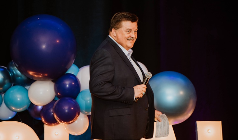Greg Westbrook speaks on stage at a past Challenge Your Fashion fundraiser for the YMCA Challenger Program