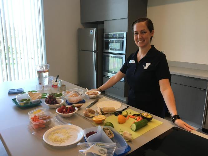 Greater Kansas City YMCA team member standing in front of a food prep table where fresh fruit and vegetables are being prepped.