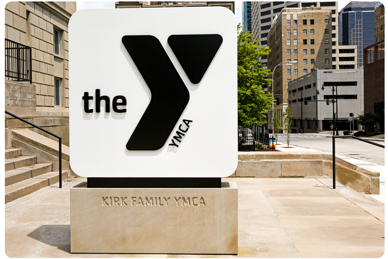Photo of monument sign outside the Kirk Family YMCA. Include black logo on white background, with Kirk Family YMCA engraved on stone base.