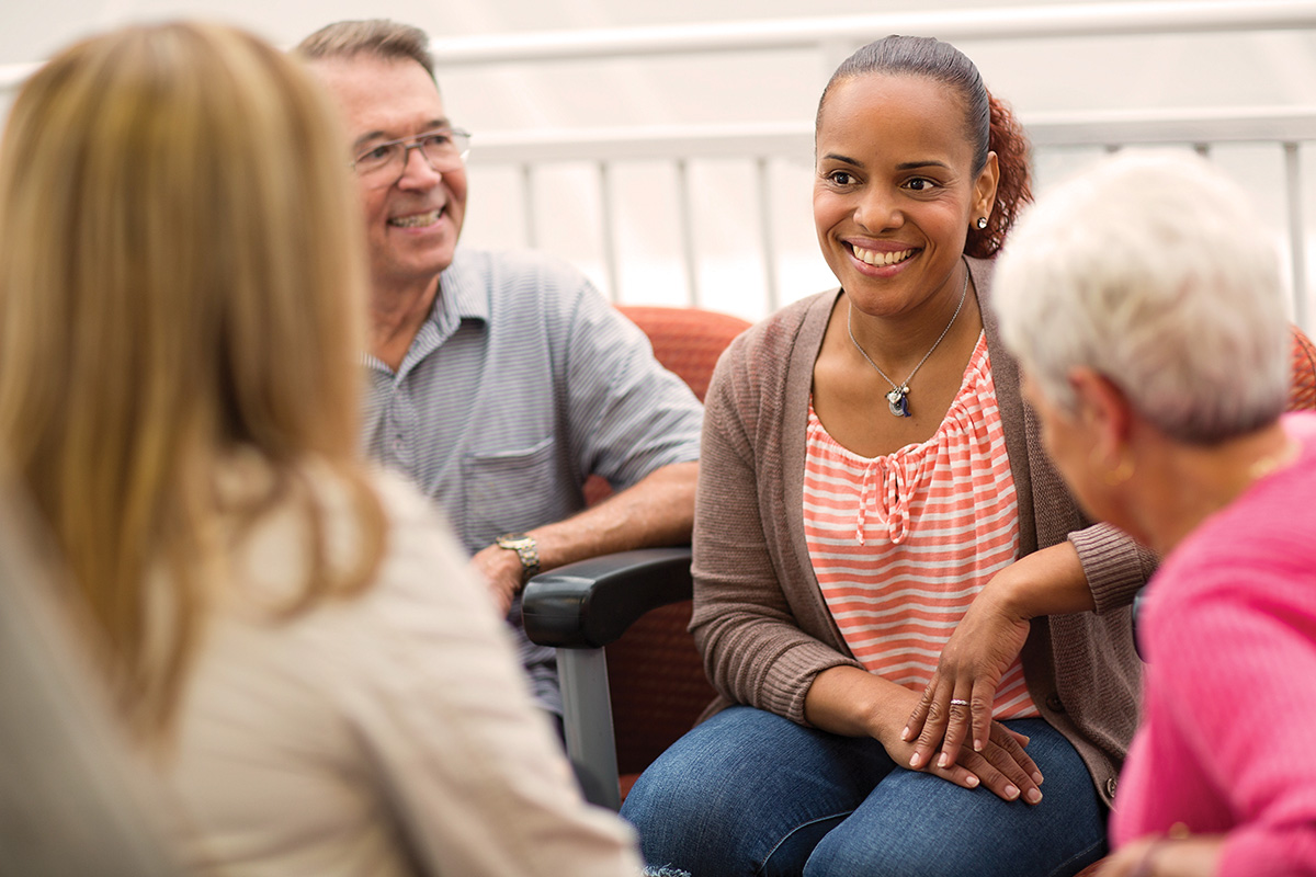 4 adults seated together smiling while talking about healthcare hosting in a Medicare Information session.