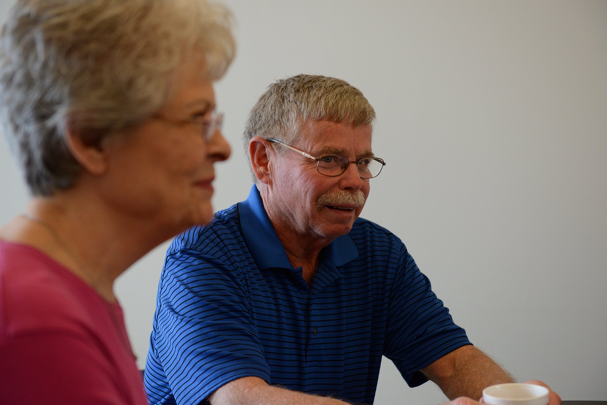 Older gentleman and woman drinking coffee while conversing.