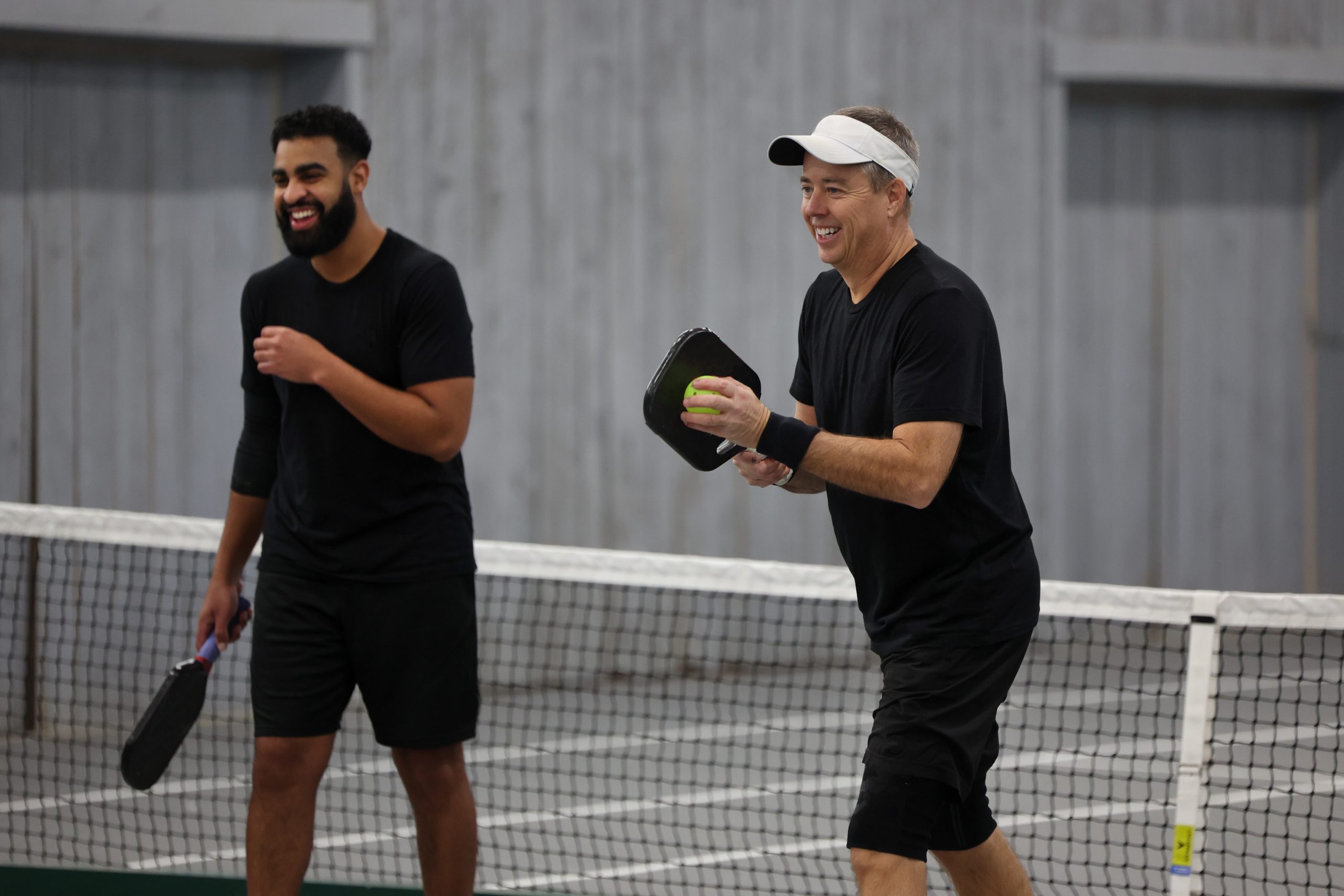 Picture of two men playing pickleball and smiling