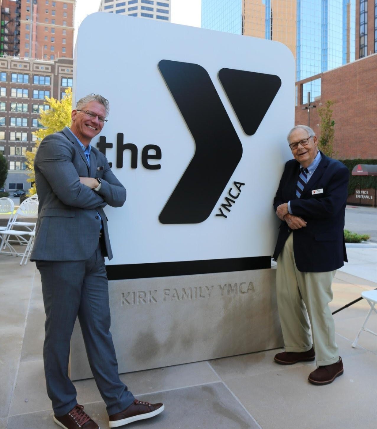 Photo of Mark Hulet and Frank Kirk in front of the Kirk Family YMCA sign.