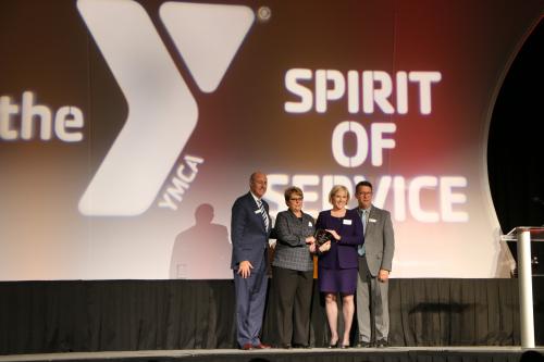 a group of four people standing on the event stage holding an award.
