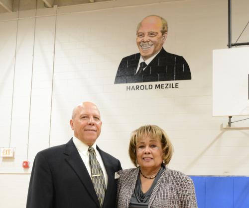 Harold and Peggye Mezile standing in front of his portrait.