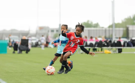 Two young soccer players compete for the ball on a green outdoor field